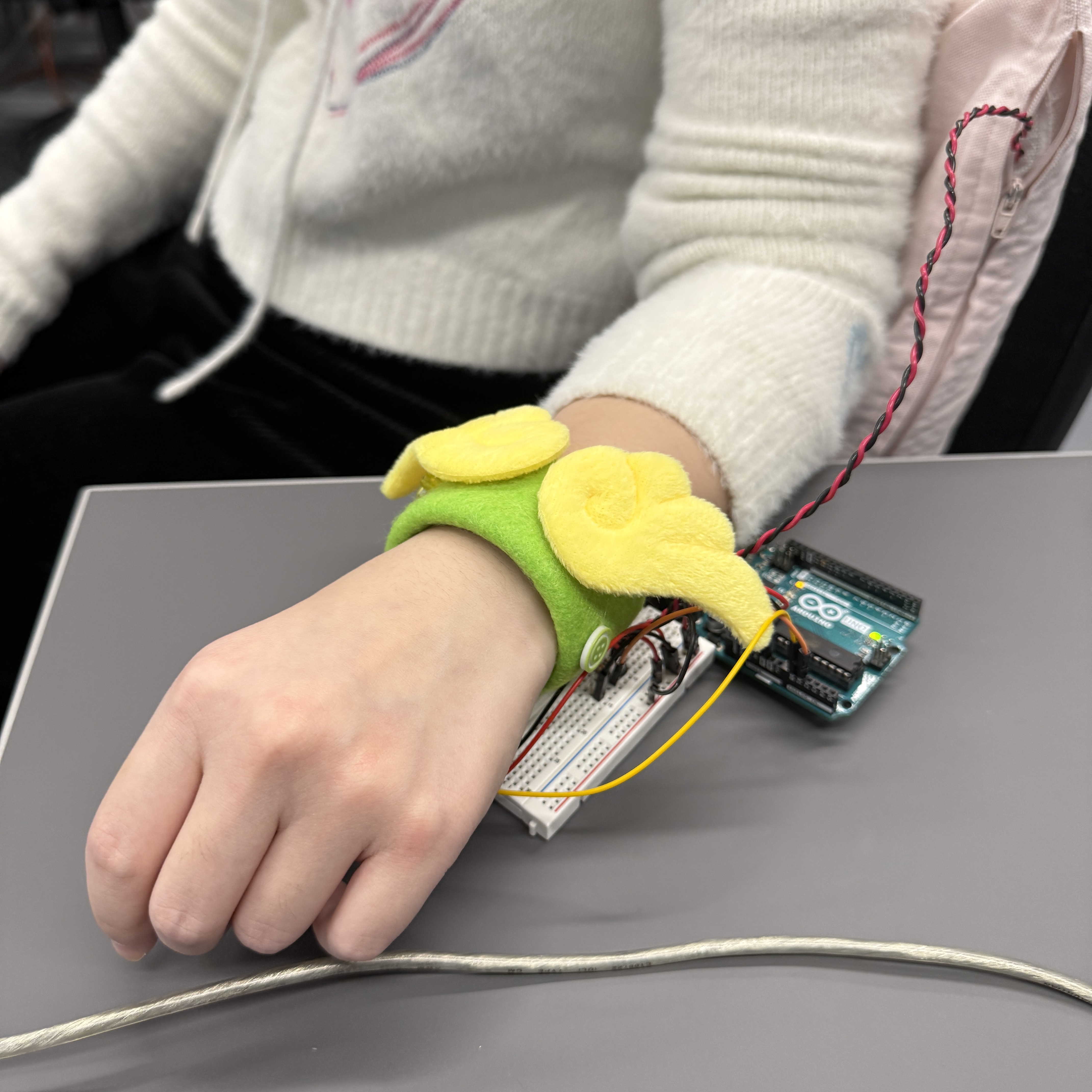 Showing the final setup of our project by lying on the cushion and having pulse sensor placed well with wrist band.